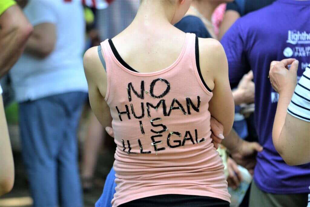 Mujer con camista que dice "No human is illegal"